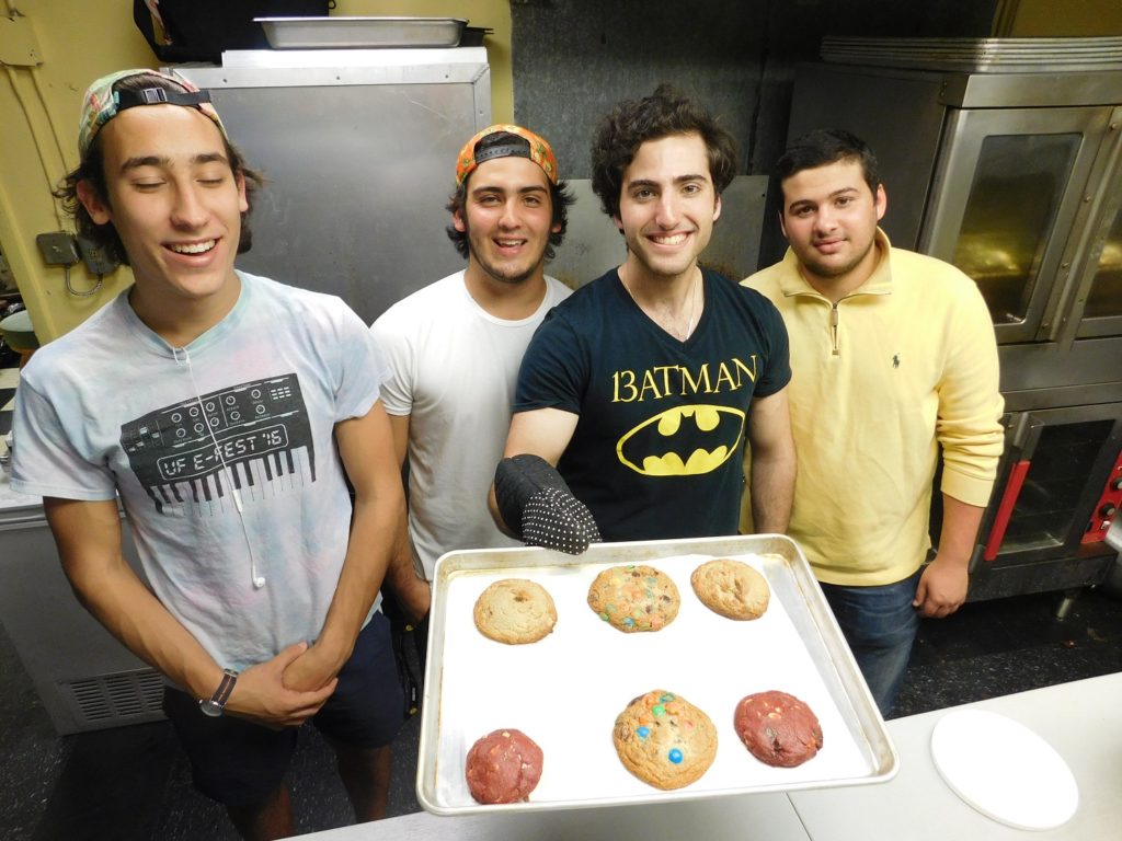 Daniel Leal (holding tray) and crewmembers, from left, Daniel Gavrilin, 19, Roberto Giorgetti, 18, and Samuel Benarroch, 20, in the Cookiegazm kitchen at Omi's.