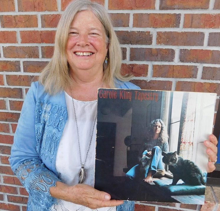 Cathy DeWitt holds the "Tapestry" album of her mentor Carole King. Photo by Gainesville Downtown)