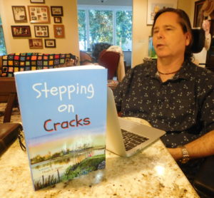 Hugh E. Suggs and his self-published novel, "Stepping on Cracks." Photo by Raphael Michael/Gainesville downtown)
