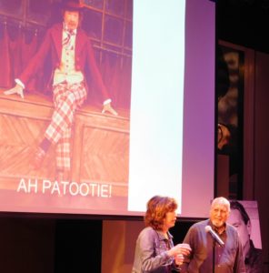 Marilyn Wall and Carlos Asse in front of a projection of Rusty Salling as Scrooge.