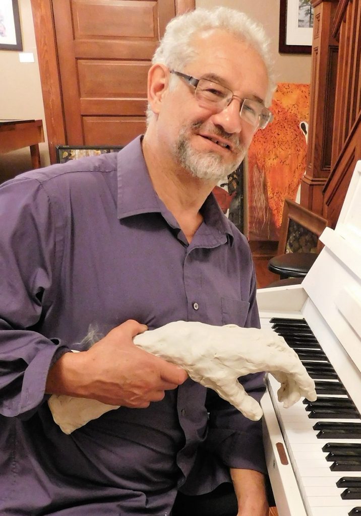 Gerard Bencen, owner of the DNA by the Hand of Man Gallery, gets a helping hand at the piano. Photo by Gainesville Downtown)